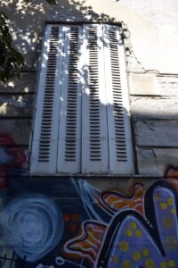 White shutters with graffiti on building wall.