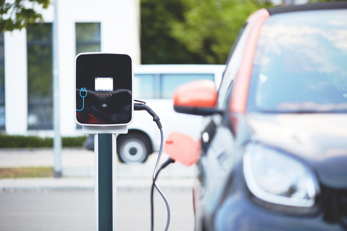 Borne de recharge électrique pour véhicule dans un parking avec voitures de location en arrière-plan