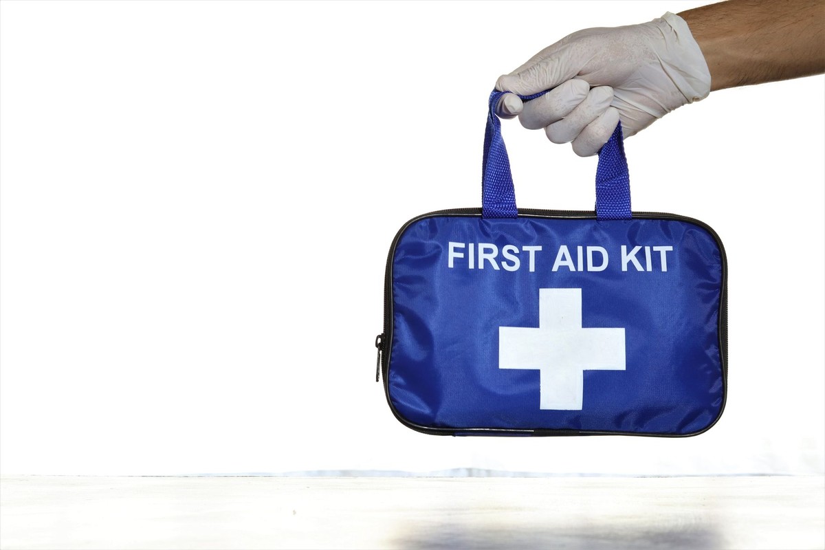 Une main gantée tient un sac bleu de premiers secours Une main gantée tient un sac bleu de premiers secours