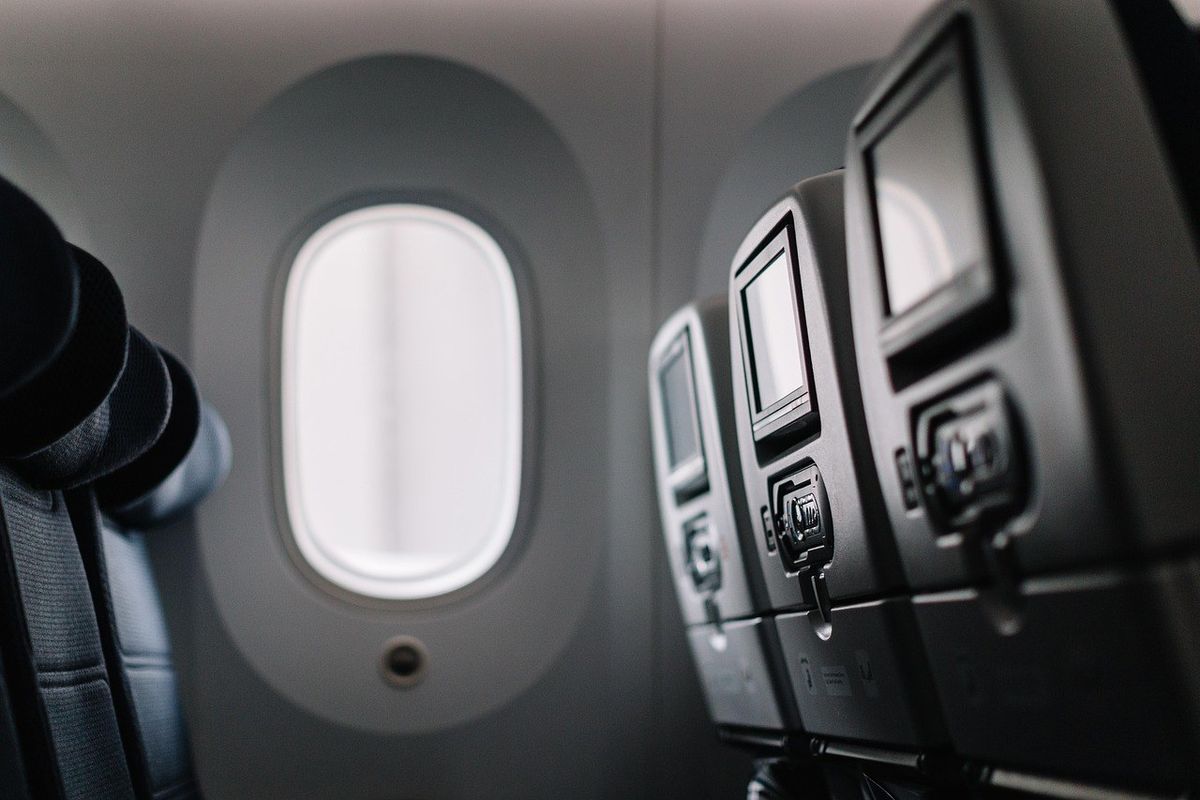 Intérieur d'avion avec sièges, écrans et fenêtre ovale
