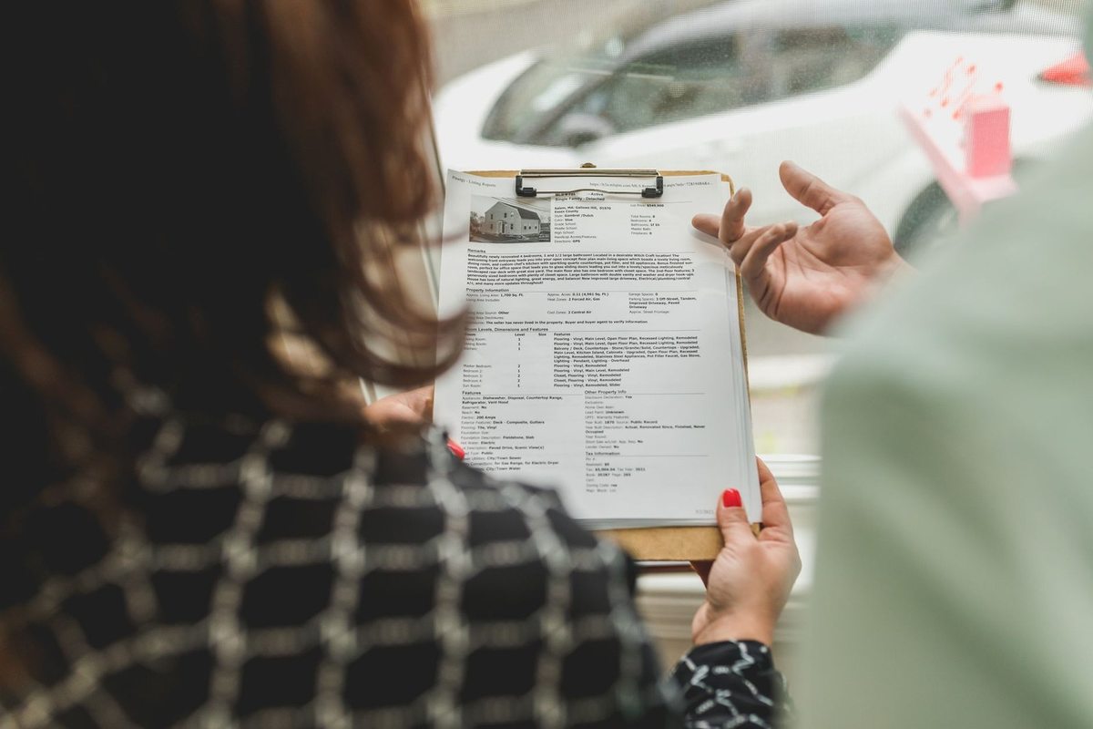 Femme examinant attentivement un document sur un plateau, main d'une autre personne proche