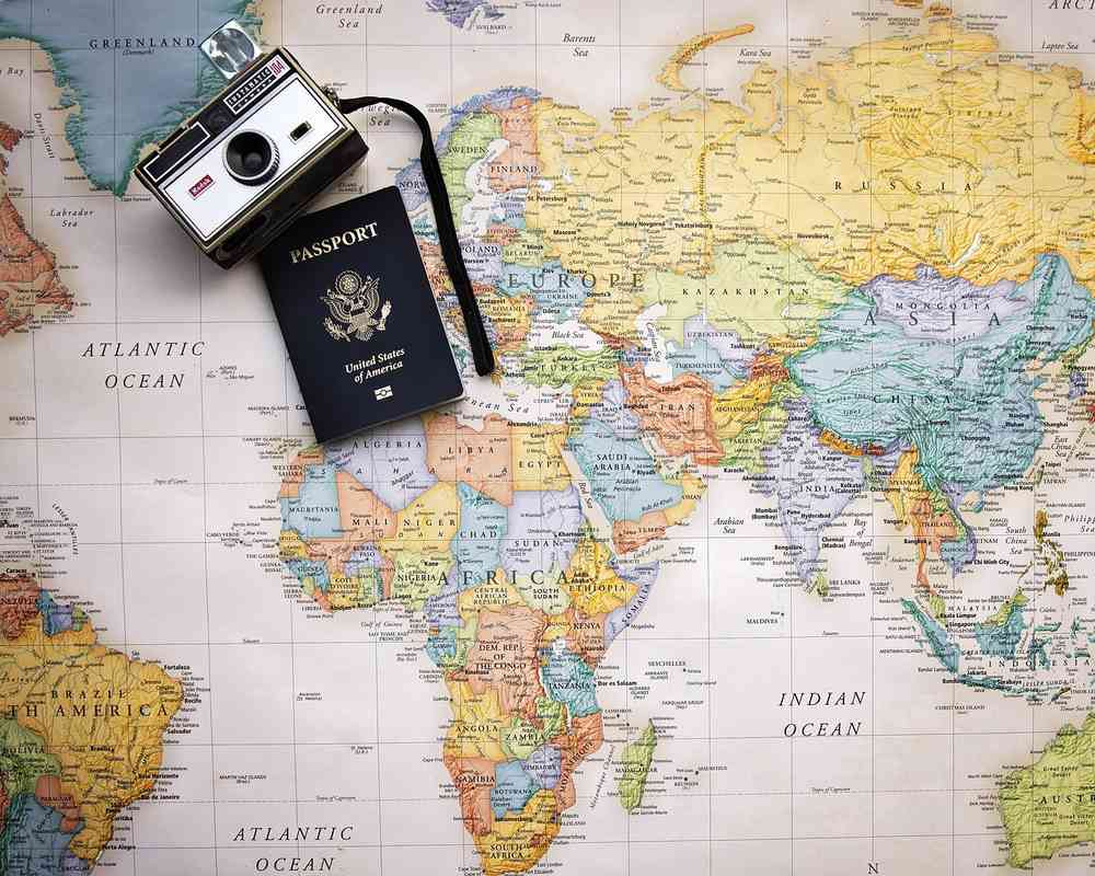 Un passeport et une caméra posés sur une carte du monde Un passeport et une caméra posés sur une carte du monde