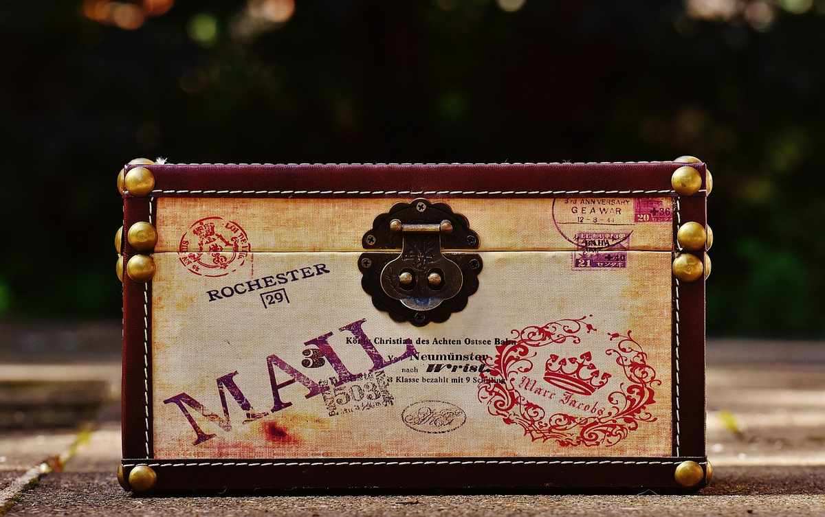 Valise vintage marron fermée avec étiquettes de voyage européennes et poignée noire Valise vintage marron fermée avec étiquettes de voyage européennes et poignée noire