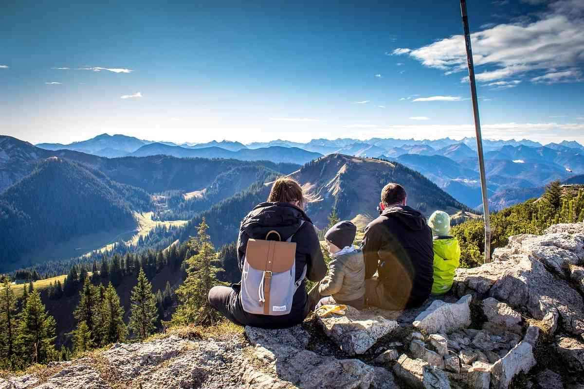 Famille admirant le panorama montagneux depuis un sommet rocheux pendant une randonnée Famille admirant le panorama montagneux depuis un sommet rocheux pendant une randonnée